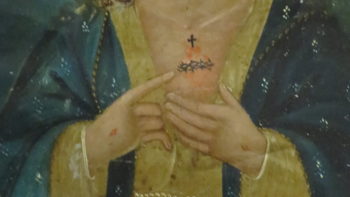 Detalle de un retablo popular mexicano: las dos manos de Cristo señalan el corazón coronado de espinas y rematado por una cruz, sobre la túnica dorada y el manto azul